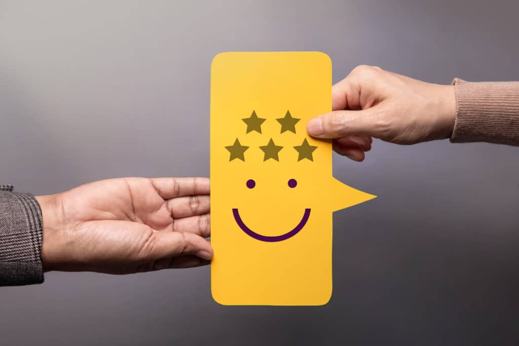 Main tenant une carte de satisfaction client avec smiley