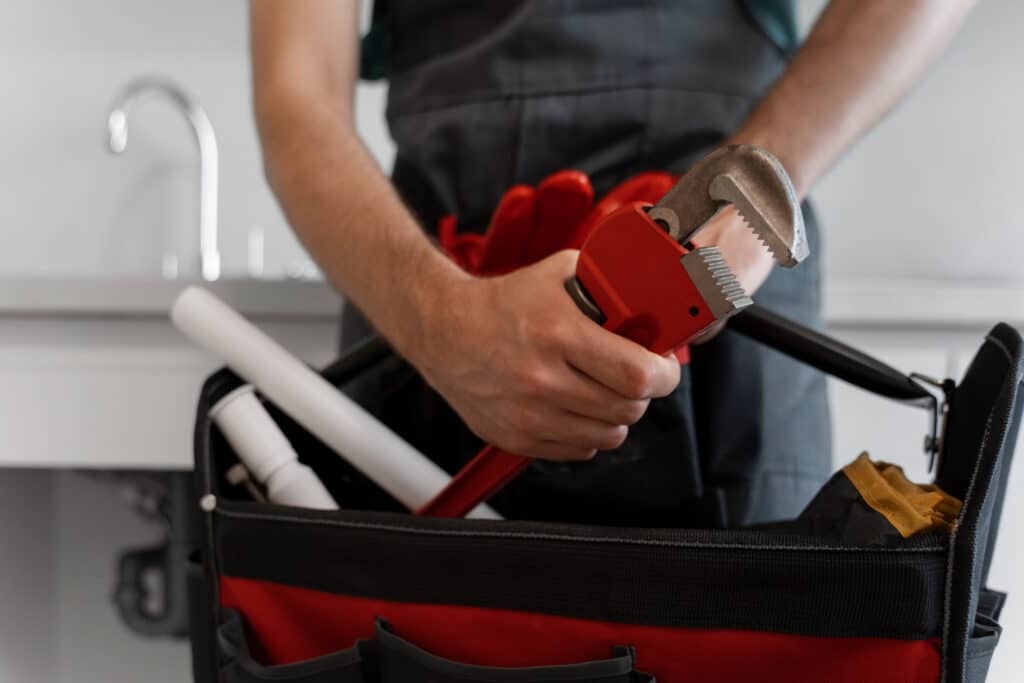 Mains d’un technicien saisissant une pince dans une boîte à outils